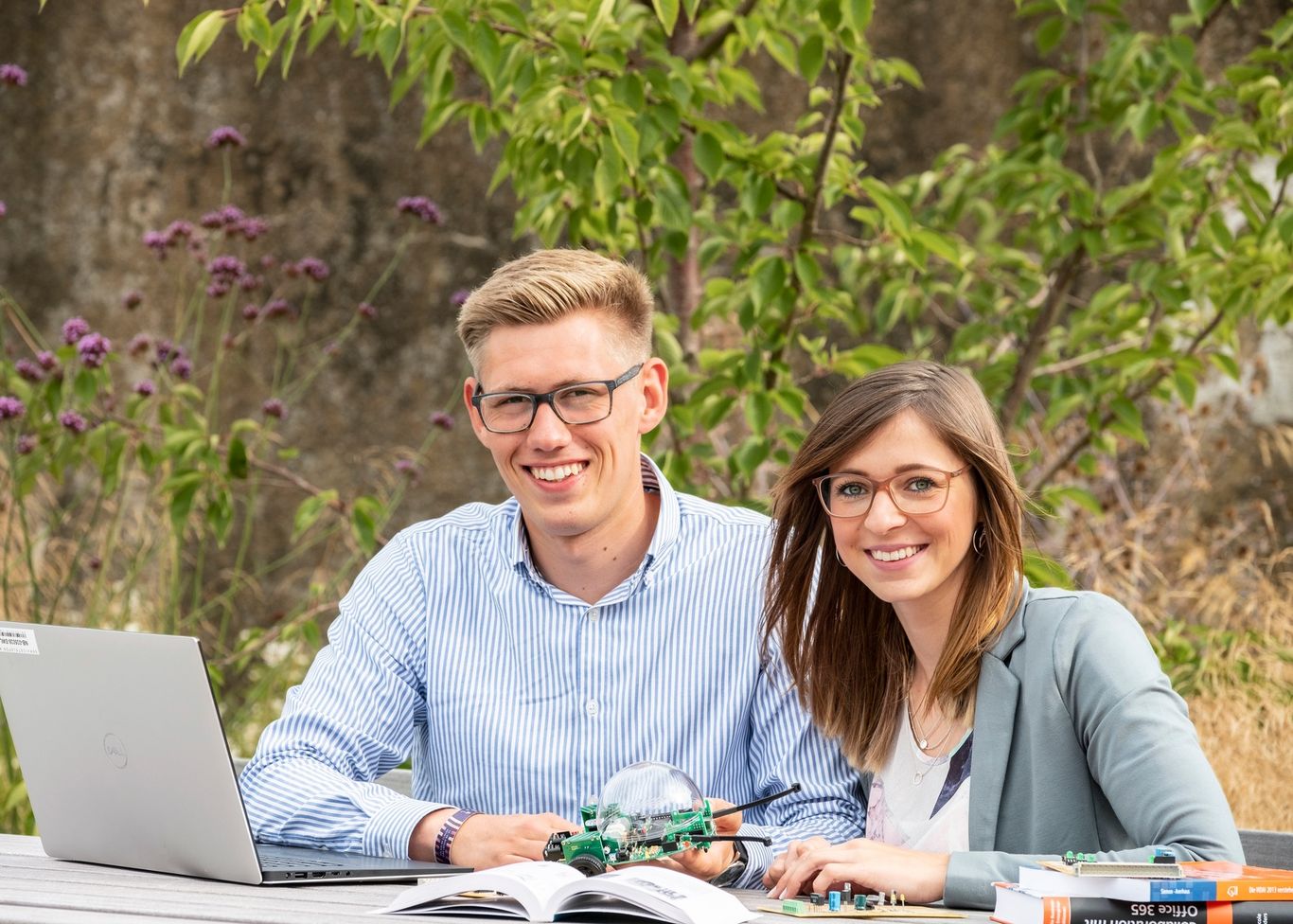 Ein Werkstudent und eine Werkstudentin arbeiten gemeinsam an einem technischen Projekt mit Laptop und Elektronik.