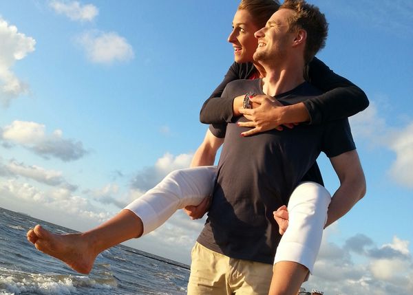 Pärchen am Strand in die Sonne schauend