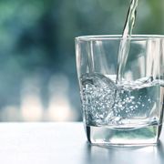 Wasser wird in ein Glas auf einem Tisch geschüttet