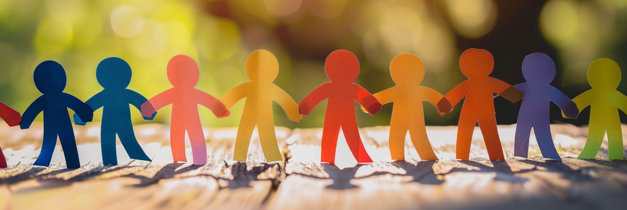Rainbow colored paper human figures holding their hands on nature background Diversity and Inclusion concept