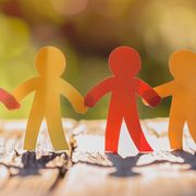 Rainbow colored paper human figures holding their hands on nature background Diversity and Inclusion concept
