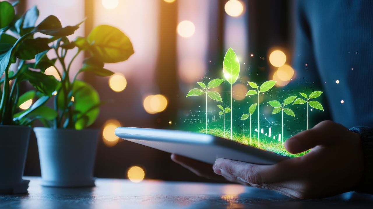 Eine Person hält ein Tablet in der Hand, auf dem digital gerenderte, leuchtende Sämlinge zu sehen sind, umgeben von Topfpflanzen und mit warmen Bokeh-Lichtern im Hintergrund (KI generiert)
